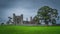 Old ruins of Christian Bective Abbey from 12th century with large green tree and field