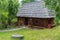 An old rural house with a thatched roof is located on a green lawn with a paved stone leading to it.