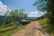 Old russian jeep parked next to wooden fence on the mountain dirty road. Summer day. Mountain tour