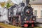 Old Russian locomotive on the railway. Old black locomotive. Smoke from the engine. Russian railway. Russia, Leningrad region