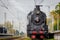 Old Russian locomotive on the railway. Old black locomotive. Smoke from the engine. Russian railway. Russia, Leningrad region
