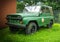 Old russian military jeep stands next to a house wall in the grass