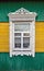 An old Russian window, a carved white clypeus. yellow-green house