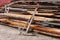 Old rusted anchor leaning against a pile of lumber to be used to repair ships