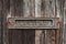 Old rusted mailbox in dark brown wooden door