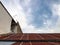 Old rusted metal roof and neighbor building house - rusted stair to the roof against cloudy blue sky