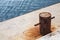 Old rusted mooring bollard on concrete pier