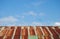 Old rusted and weathered steel quonset hut roof against a blue sky with fluff clouds