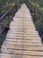 Old rustic bridge of wooden planks on a metal base with iron handrails, going into perspective