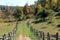 Old rustic fencing lining a grassy pathway into the woods