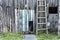 Old rustic gray blue wooden plank wall with dog walkway door and wooden staircase, white horseshoe above the entrance