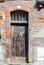 Old rustick brown narrow tall wooden door in historic house in T