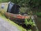 Old rusting houseboat overgrown with weeds moored on the rochdale canal listing to one side and beginning to sink