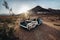 Old rusty abandoned car in the desert at sunset time.