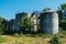 Old rusty abandoned oil tanks with stairs overgrown by trees