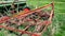 Old, rusty and abandoned red agricultural cultivator next to an old tractor