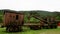 Old, rusty and abandoned waggon placed at a grass field with hills behind it