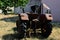 Old rusty agricultural tractor parked on lawn in backyard of Croatian house