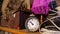 Old rusty alarm clock stands on a wooden shelf on the background of junk. Timeless and garage sale concept