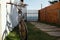 Old rusty bicycle in the rays of sunlight in the backyard of white house near the sea. Red Brick wall