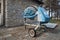 An old rusty blue bent two-wheeled electric concrete mixer