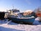 Old rusty boat moored to the shore in the winter froze on the river