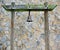 Old Rusty Bronze Metal Bell Hanged on A Green Mossy Wood  Pillar In A Stone Pattern Wall