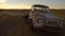 Old rusty car in a field in Australia with sunset in the background