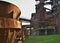 Old rusty cup for casting steel on a green field in an abandoned steelworks factory