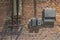 Old rusty electrical panel with buttons and wires and water pipes with taps on the ragged red brick wall of the factory