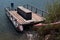 Old rusty floating platform with wooden floor and bench in the middle, serving as molo in yacht club.