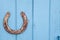 Old rusty horseshoe on wooden blue background.