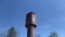 Old rusty leaking water tower against the blue sky.