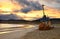 An old rusty longboat against the background of a fiery sky at sunset