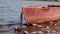 Old rusty metal boat chained on a river bank on sunny day