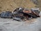 Old rusty metal manhole covers and storm grates piled up near a pile of sand