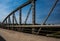 Old rusty metal railings on the bridge. Road with cracked asphalt