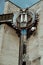 Old, rusty, metal timepiece in form of owl on building. Vintage, big, electronic clock on street in cloudy weather.