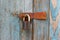 An old rusty padlock on an old cracked wooden door covered with old peeled blue paint