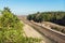 Old rusty railriad track curve among evergreen coniferous pine forest and blue sky on background