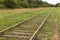 Old rusty railway with wooden sleepers in the forest overgrown with grass