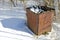 Old rusty rubbish container on snow