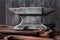 Old rusty rugged anvil on top of other blacksmith tools.