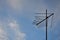 An old and rusty television antenna against a cloudy blue sky