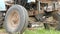 An old rusty tractor stands near the field. The machine for agriculture is waiting for the processing of the field