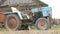 An old rusty tractor stands near the field. The machine for agriculture is waiting for the processing of the field