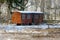 Old rusty trailer with windows in the snow in the overgrown park