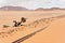 Old rusty unused railroad switch at Wadi Rum train station, tracks covered with sand near, desert and mountains in