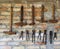 Old rusty work tools hung on a brick wall. A row of hammers of different size and a row of ancient pliers underneath
