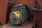 An old rusty working stationary engine stands on a locksmith`s chair. The engine has no blades and casing.